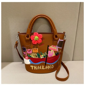 Close-up of brown bucket bag with colorful 3D embroidery and Thailand text detail