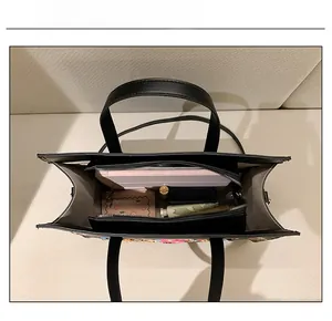 Spacious interior of black embroidered tote bag holding a tablet and cosmetics