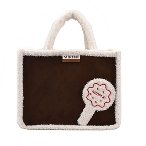 Brown suede tote bag with white faux shearling trim and top handles in a classic minimalist style