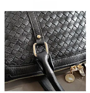 Détail de la texture cuir tressé noir avec garnitures dorées et curseur de fermeture éclair