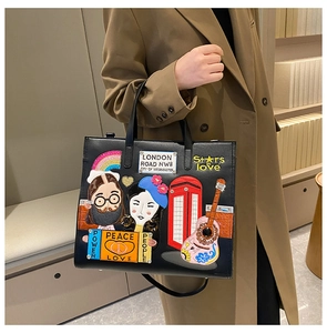 Close-up of black leather tote bag with colorful London-style embroidery and patches