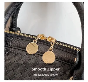 Détail de la double fermeture éclair dorée sur le sac à main en cuir tressé noir