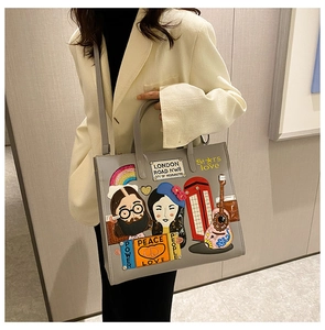 Detailed close-up of grey leather tote with colorful embroidered London themed patches