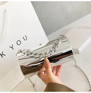 Détail de ce sac cylindrique argenté brillant avec poignée à grosse chaîne et fini miroir