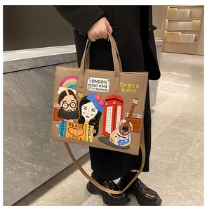 Detail of khaki tote bag featuring London-themed embroidery and cartoon character patches