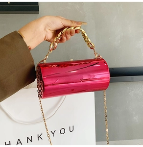 Détail du sac cylindre métallisé rose avec grosse chaîne dorée et finition brillante
