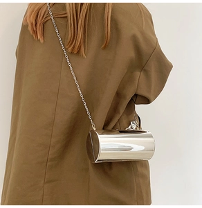 Gros plan d'un sac cylindrique argenté brillant avec chaîne en métal porté dans le dos