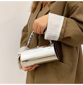 Gros plan d'un sac cylindrique argenté porté par un mannequin en blazer marron
