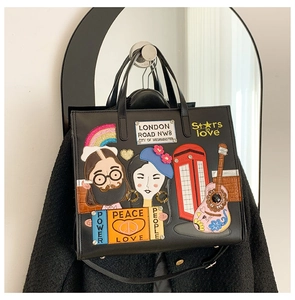 Macro shot of colorful embroidery and London-themed patches on a black tote bag