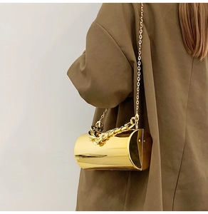 Détail d'un sac cylindrique doré brillant avec chaîne et poignée tissée épaisse