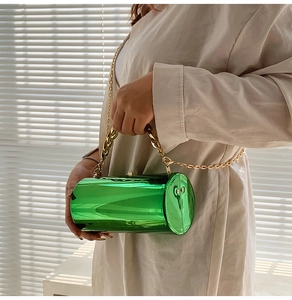 Détail du sac cylindrique vert émeraude métallisé avec chaîne dorée et finition miroir éclatante