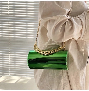 Détail du sac cylindre vert vif avec finition miroir métallique et grosse chaîne dorée