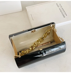 Détail du sac cylindrique noir brillant avec chaîne dorée et doublure beige