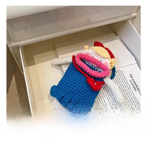 Détail d'une poupée au crochet faite main avec corps bleu et col rose dans un tiroir blanc