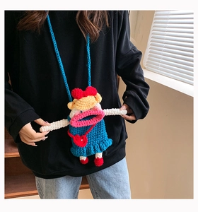 Détail d'un sac bandoulière au crochet bleu avec grande bouche rose et nattes jaunes