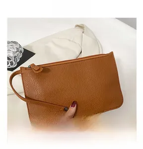 Detail view of a brown pebbled leather wristlet pouch with a secure zipper closure