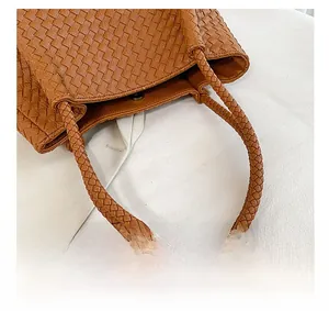 Detail view of woven faux leather bag with round braided handles and silver magnetic clasp
