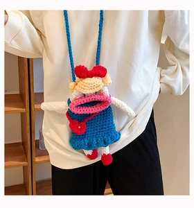 Détail du sac au crochet bleu avec ouverture en forme de lèvres roses et nœud rouge