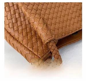 Close-up of reinforced handle and premium brown woven leather texture on tote bag