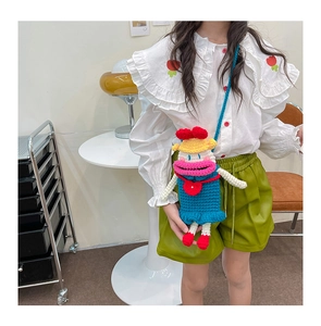 Détail du sac à bandoulière bleu au crochet avec bouche rigolote porté par le modèle