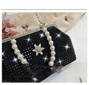 Détail de la poignée en perles avec ornement de fleur en strass sur un sac de soirée noir
