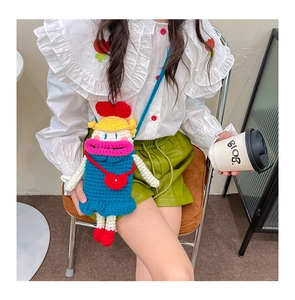 Détail d'un sac à bandoulière en crochet fait main avec un personnage aux grosses lèvres