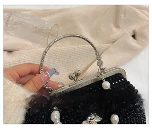 Détail du sac de soirée noir avec strass et anse en métal argenté et breloque en perles