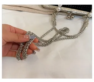 Détail de la bandoulière métallique argentée et fermoir perle sur pochette noire