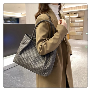Dark grey woven leather tote bag shown on a model in a professional commuting setting
