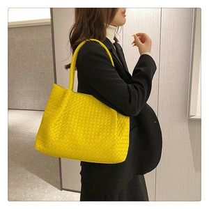 Close-up of bright yellow woven tote bag showing premium leather texture and knot detail