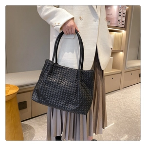 Close-up of black woven leather tote bag texture and soft cylindrical handles