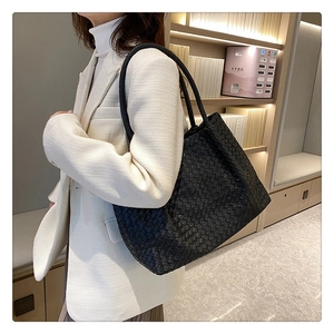 Detail of black woven leather tote bag with Intrecciato craft on a white blazer model