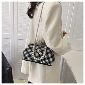 Détail du sac de soirée noir en strass avec poignée en perles et ornement étoile sur blazer