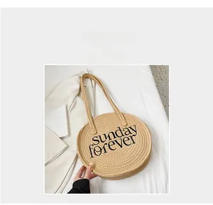 Detail of round straw bag featuring Sunday Forever embroidery and textured woven pattern