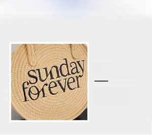 Detailed view of woven straw bag texture and black embroidered Sunday Forever lettering