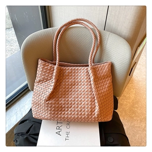 Close-up of pink woven leather tote showing intricate craftsmanship on a soft chair