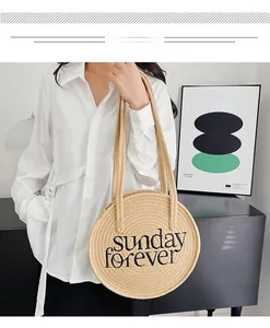 Detailed shot of a woven round straw shoulder bag featuring Sunday Forever embroidery