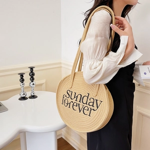 Detail of Sunday Forever embroidery on a beige woven round shoulder straw beach bag