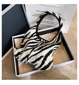 Dettaglio borsa shopper in maglia con motivo a onde bianco e nero in confezione regalo