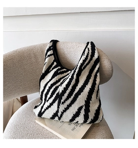 Dettaglio della borsa tote in maglia zebrata con texture intrecciata su una sedia velluto
