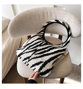 Borsa tote in maglia con motivo zebrato bianco e nero su una sedia in pile morbido