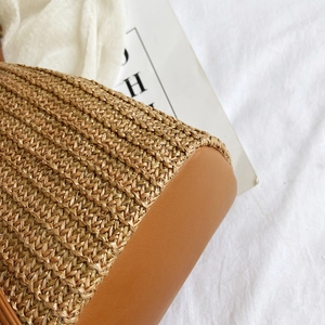 Close-up of woven straw texture and premium brown leather base on a bucket bag