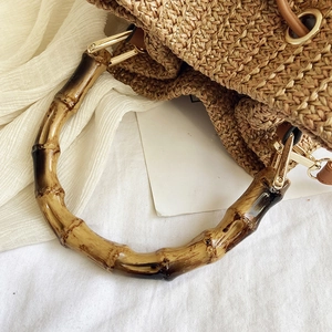 Close-up of woven straw bucket bag with natural bamboo handle and leather drawstring closure