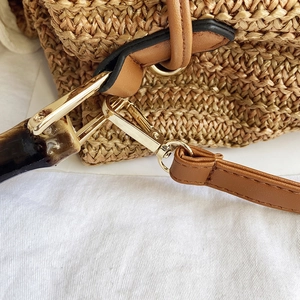 Detail of woven straw texture with bamboo handle and premium metal clasp on bucket bag