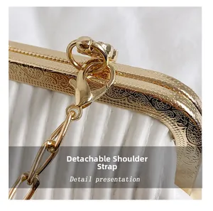 Close-up of golden vintage engraved clasp and detachable chain strap on white evening bag