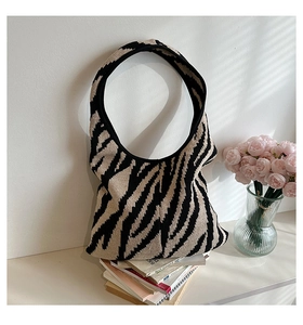 Dettaglio di una borsa hobo in maglia con motivo zebrato e trama in materiale intrecciato