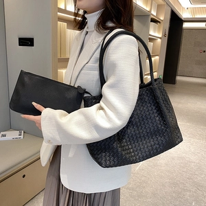 Women's black woven leather tote and matching pouch set worn with white blazer