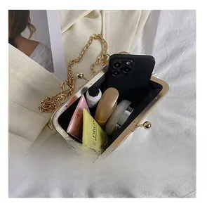 Detail of white pleated cloud clutch with gold frame showing large interior capacity