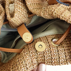 Detail view of woven straw bucket bag with magnetic closure and green canvas lining