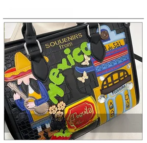 Détail de la broderie mexicaine sur sac cabas en cuir noir avec motifs de cactus et guitare